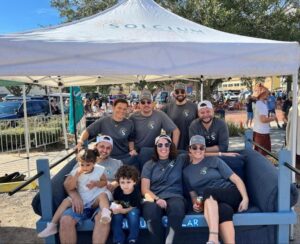 members of the Solcium Solar team seated around a couch at the Sofa N Suds community event in downtown Sanford, Florida