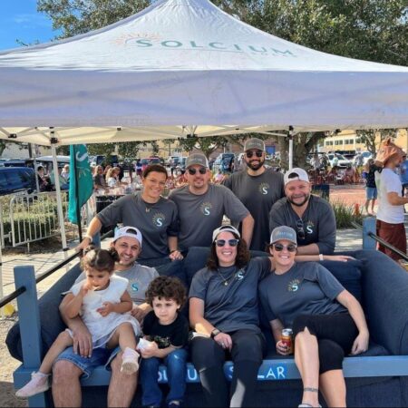 members of the Solcium Solar team seated around a couch at the Sofa N Suds community event in downtown Sanford, Florida