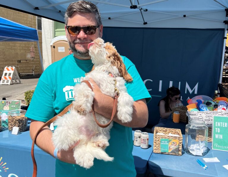 Solcium Solar's CS), Gustavo Panosso, holding a puppy at Sanford's Paws & Pints event