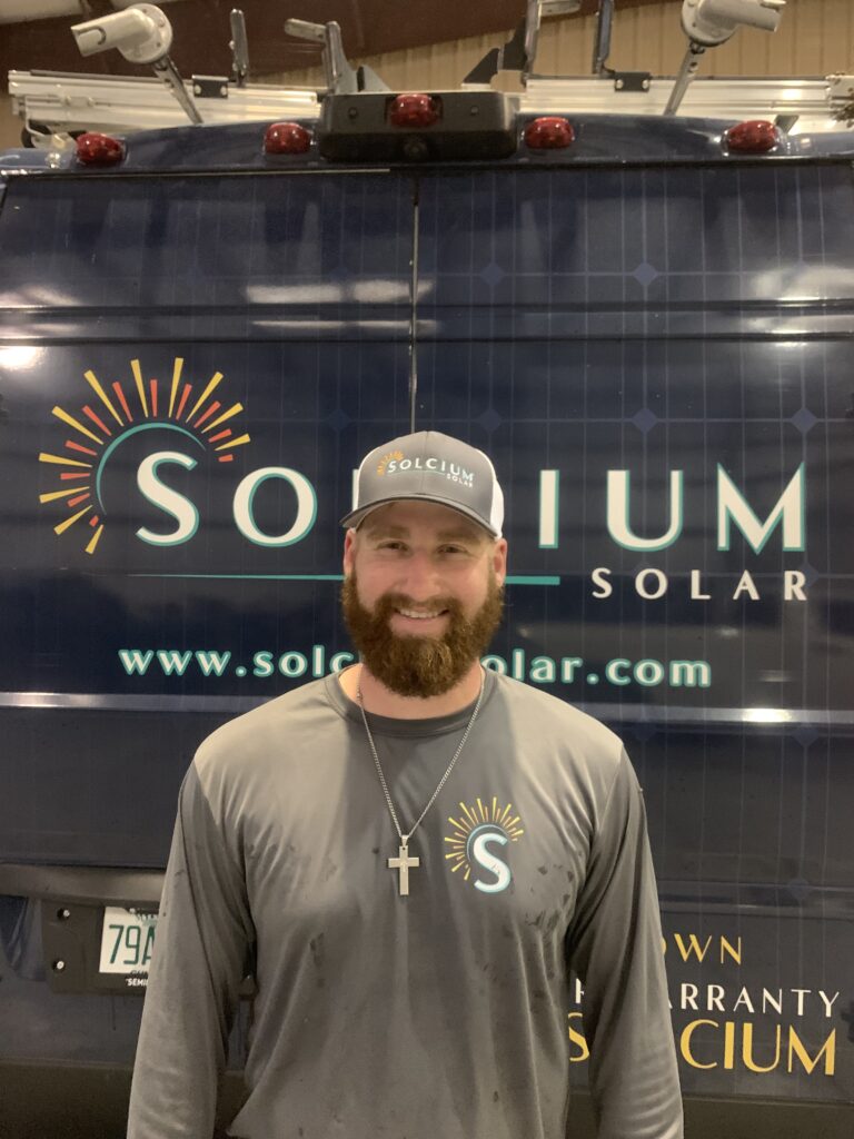 Solcium Solar lead electrician, bryson apple, poses in front of a Solcium fleet vehicle to celebrate Veterans Day.