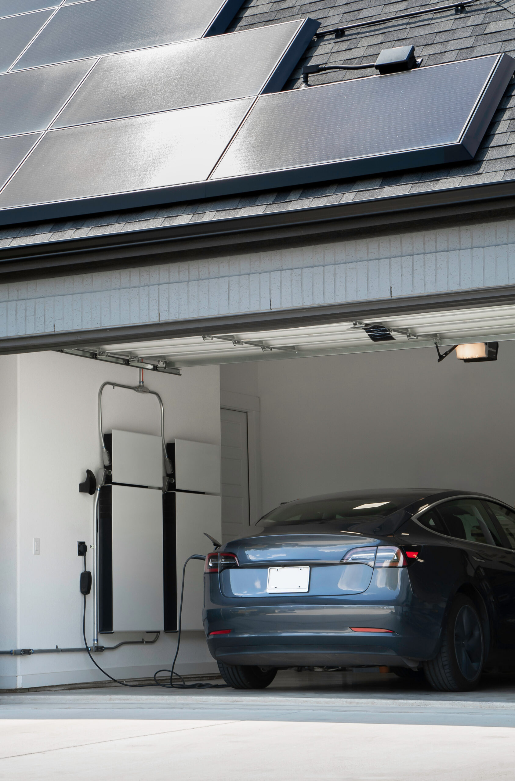 Electric Vehicle in the garage of a home with solar panels on the roof