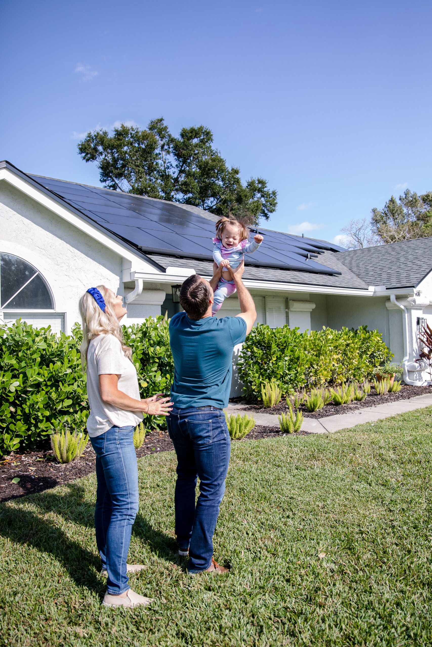 happy couple with daughter in the arms of a father in front of a home with solar celebrating their pearl certification value