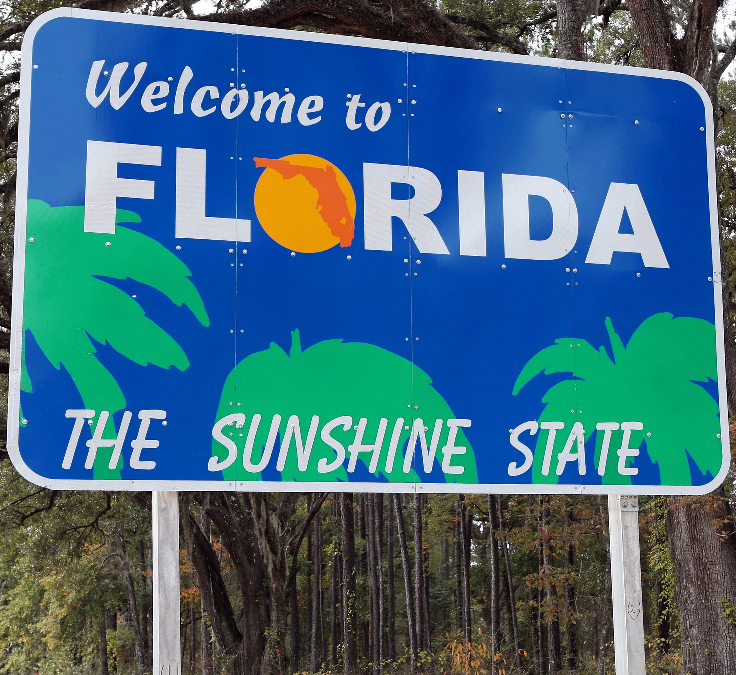 blue sign with palm trees on it that reads "Welcome to Florida, The Sunshine State"