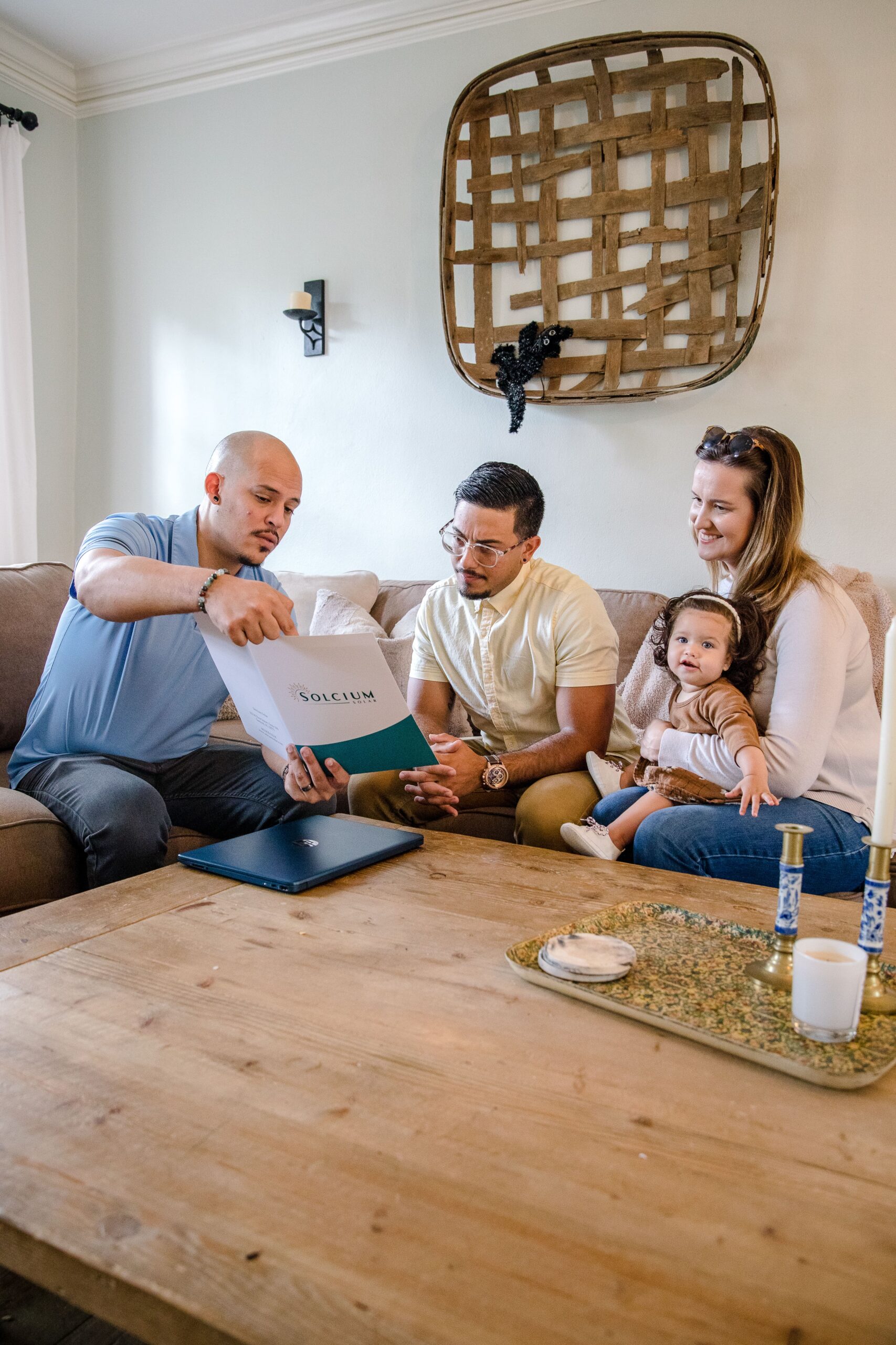 Solcium Solar's energy consultant shows a folder of solar information to an inquiring couple on a couch inside their home.