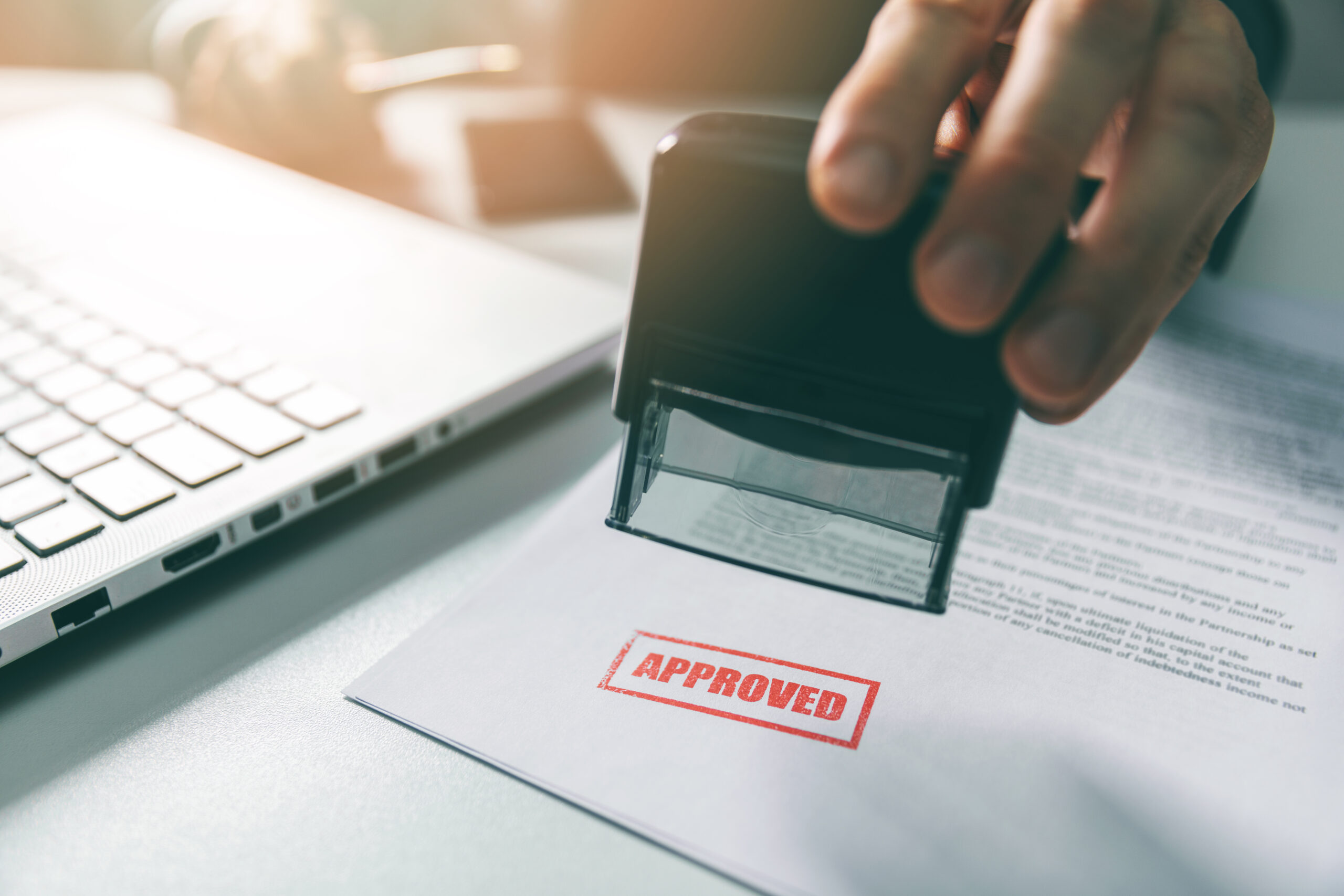 Business person stamps a permit application with a stamp that reads "Approved".