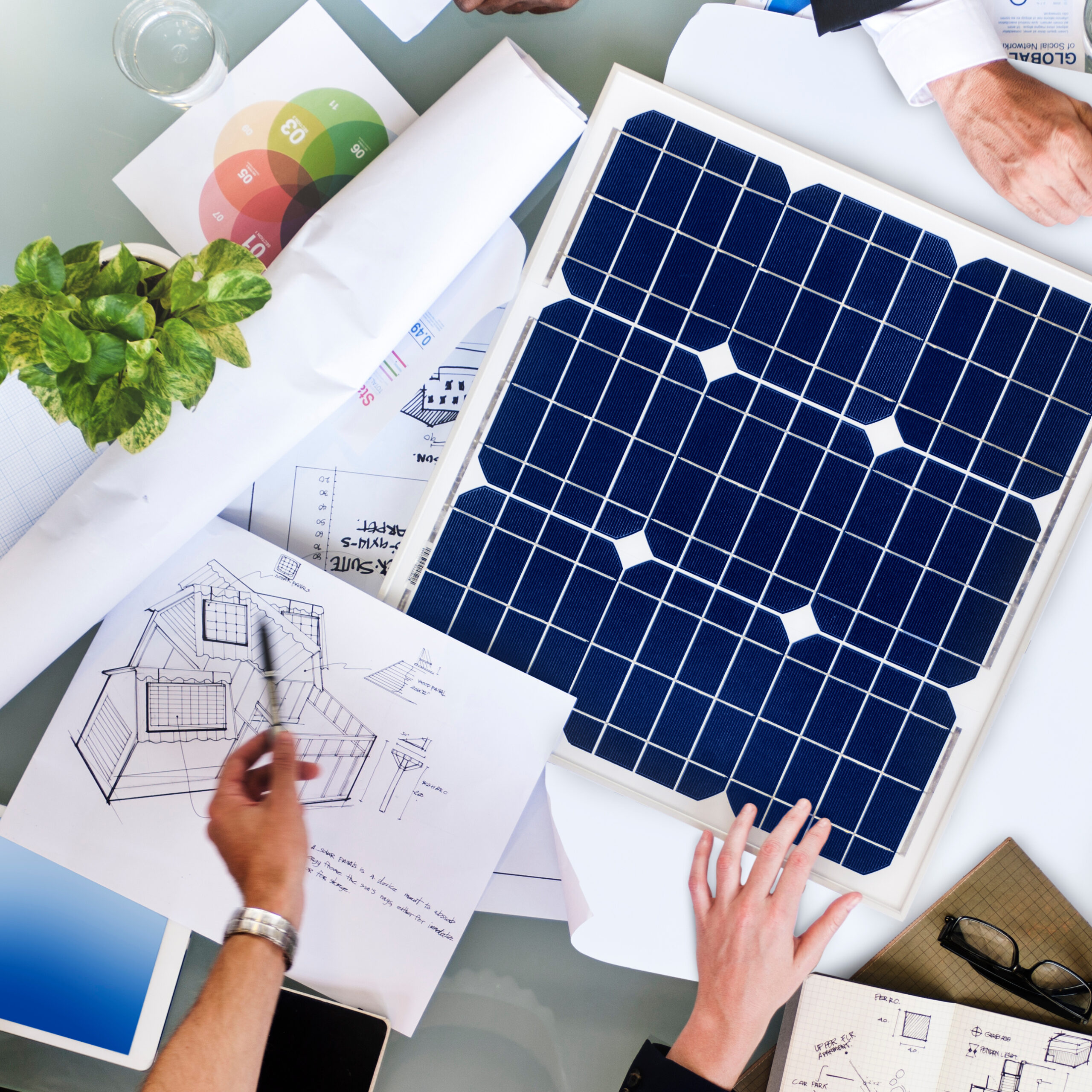 Solcium Solar team discussing the design of a solar energy system while standing over plans and drawings of the system.