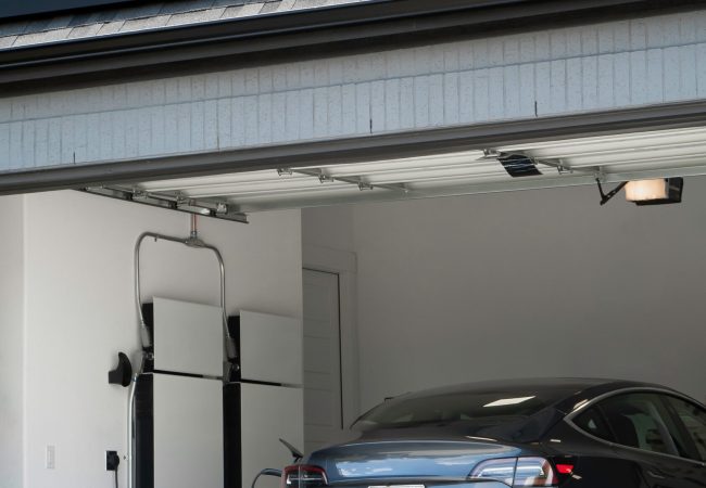 Electric Vehicle in the garage of a home with solar panels on the roof